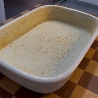 Una casseruola bianca è appoggiata su un tavolo a scacchi