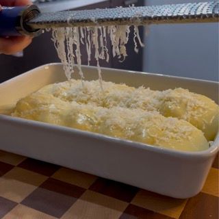 Una persona che grattugia il formaggio in una casseruola