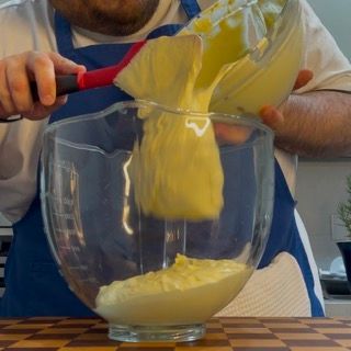 Un uomo sta versando qualcosa in una ciotola con una spatola