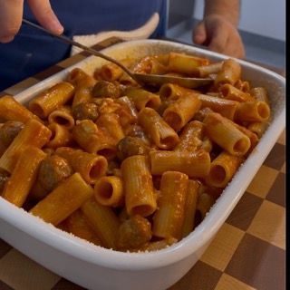 Una casseruola piena di pasta e polpette su un tavolo a scacchi