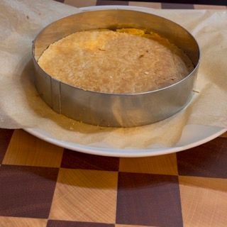 Una torta rotonda su un piatto bianco su un tavolo a scacchi