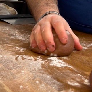 Una persona sta impastando una palla di pasta su un tavolo