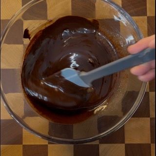 Una persona sta mescolando il cioccolato in una ciotola con una spatola