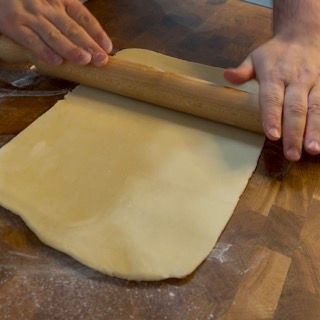 Una persona sta stendendo un pezzo di pasta con un mattarello