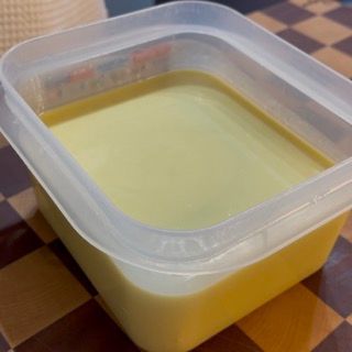 Un contenitore di plastica pieno di liquido giallo su un tavolo a scacchi