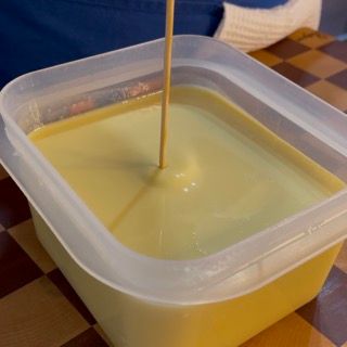 Un contenitore di plastica pieno di liquido giallo e un bastoncino dentro