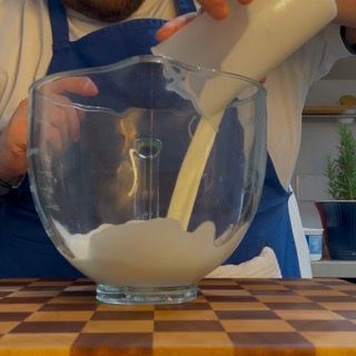 Un uomo sta versando il latte in una ciotola di vetro