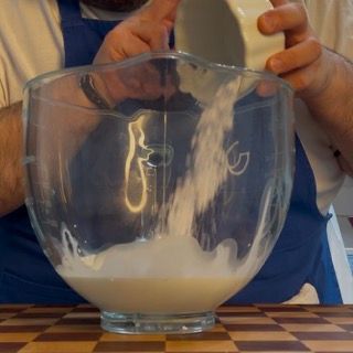 Un uomo sta versando il latte in una ciotola di vetro