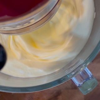 Primo piano di una ciotola di vetro piena di panna montata.