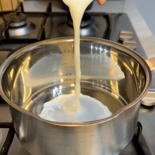 Una persona sta versando del liquido in una pentola sul fornello