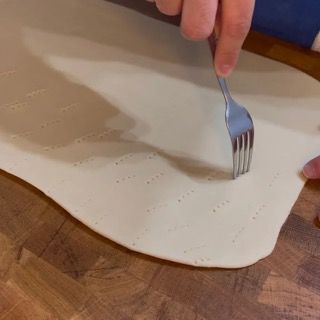 Una persona tiene una forchetta sopra un pezzo di pasta