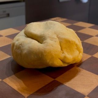 Una palla di pasta è appoggiata su un tagliere a scacchi