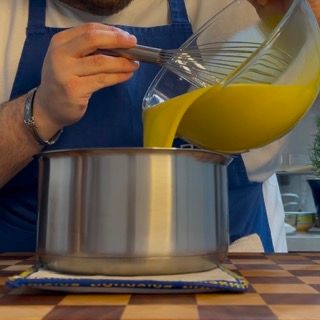 Un uomo sta versando del liquido giallo in una pentola