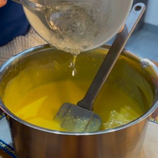 Una persona sta versando del liquido in una pentola con un cucchiaio