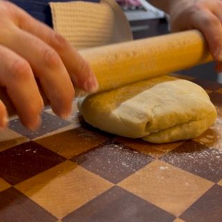 Una persona sta stendendo la pasta con un mattarello