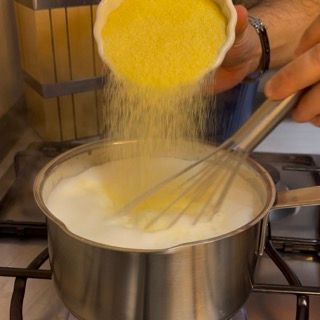 Una persona sta versando il mais in una pentola di latte