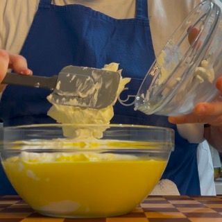 Una persona sta versando il burro in una ciotola con una spatola