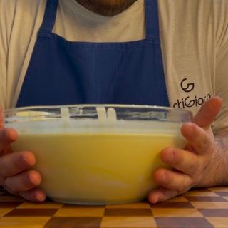 Un uomo che indossa un grembiule tiene in mano una ciotola di cibo