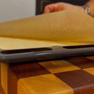 Una persona tiene in mano un pezzo di carta sopra un tagliere di legno