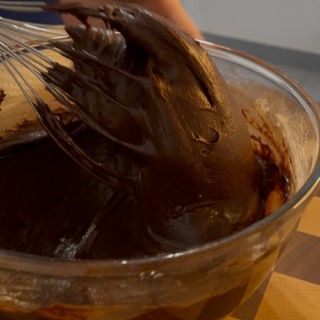 Una persona sta sbattendo il cioccolato in una ciotola di vetro