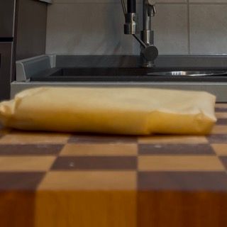 Un pezzo di burro è appoggiato su un tagliere di legno davanti al lavandino della cucina.