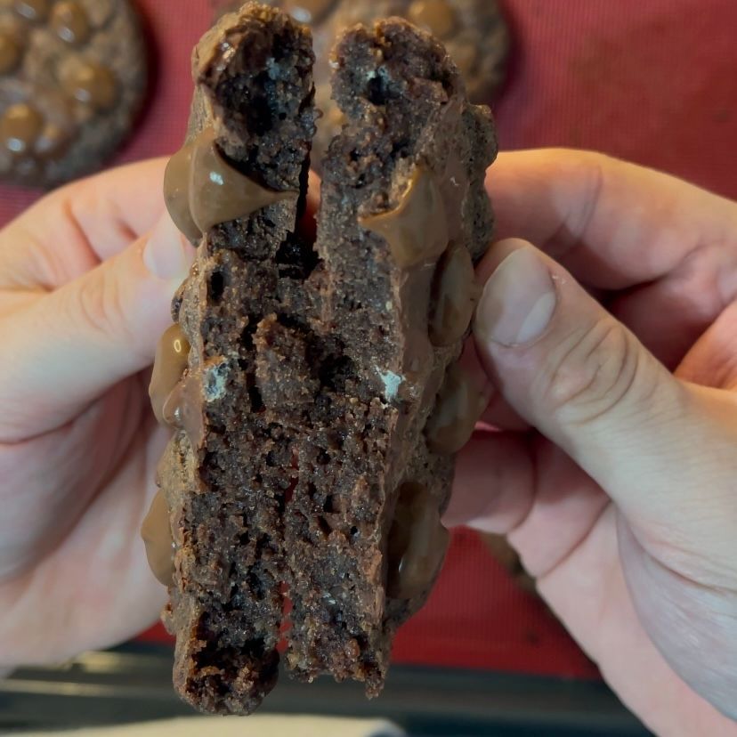 Una persona tiene in mano un biscotto al cioccolato con un morso