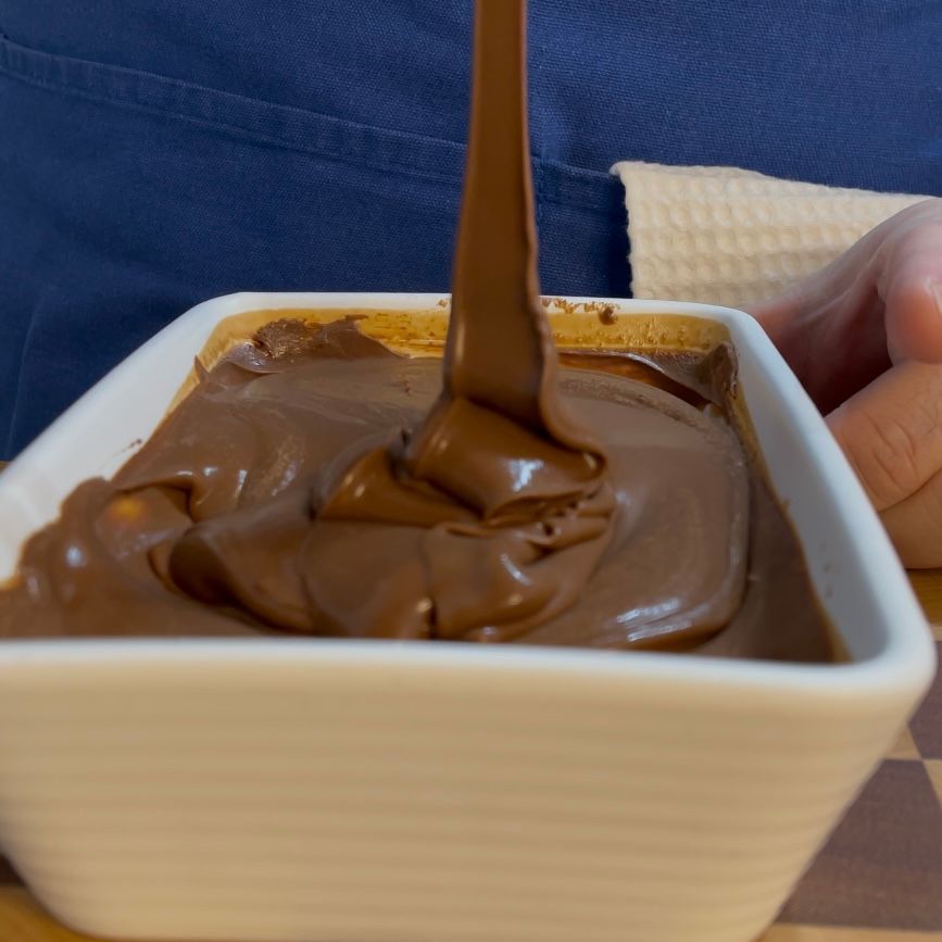 Una persona sta versando del cioccolato in una ciotola bianca