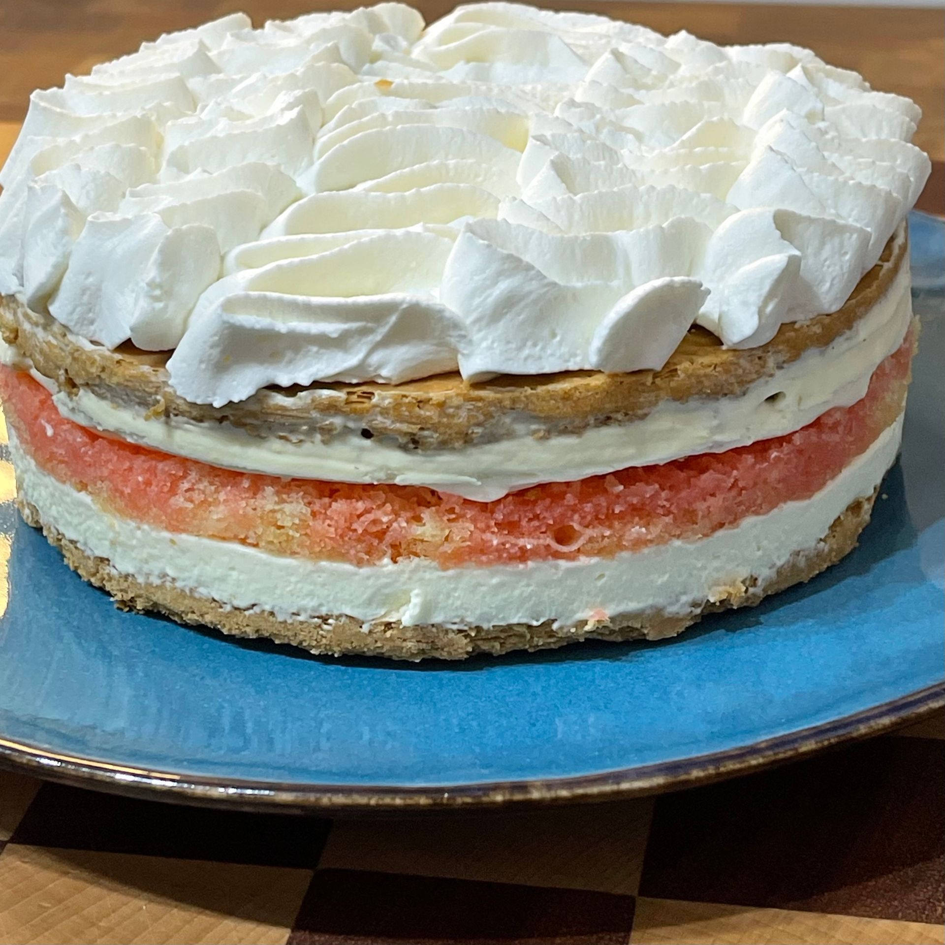 Una torta con panna montata sopra è su un piatto blu