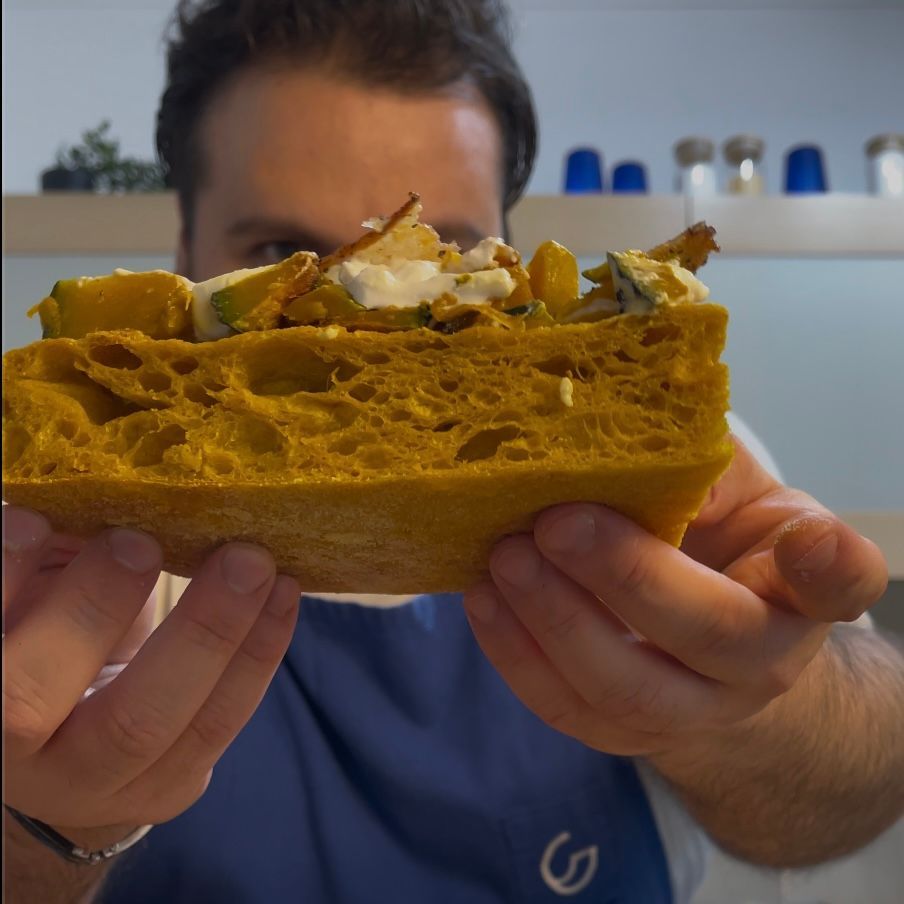 Un uomo con un grembiule blu tiene in mano un pezzo di cibo