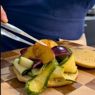 Una persona tiene le pinze sopra un panino su un tagliere