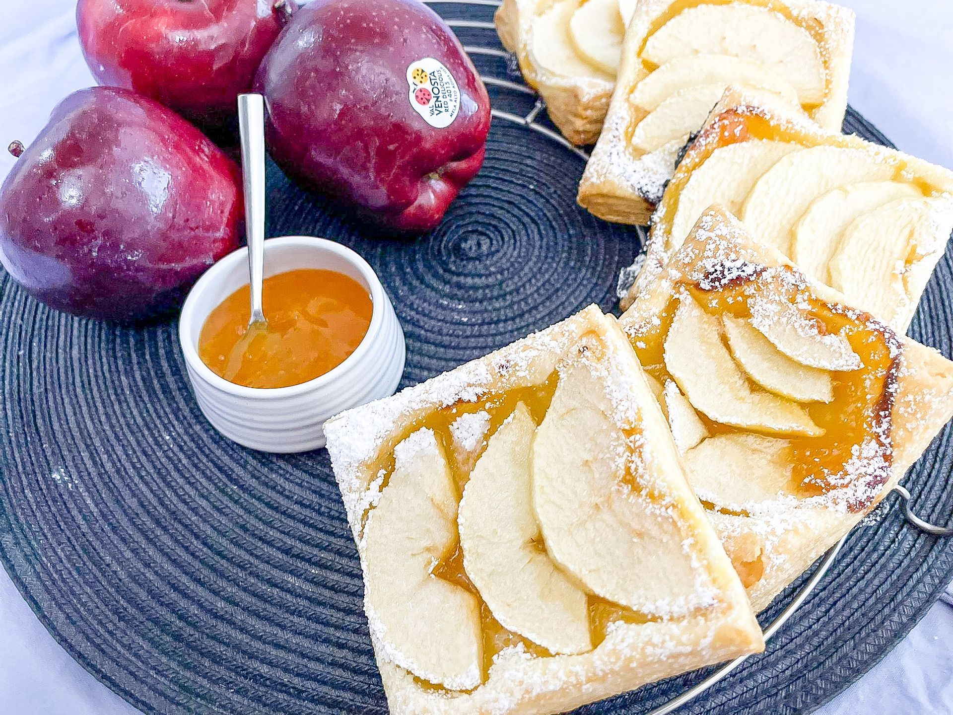 Un piatto di cibo con mele e una ciotola di marmellata su un tavolo.