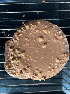 Un biscotto al cioccolato con sopra delle noci è su una griglia di raffreddamento