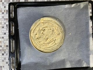 Un cerchio di pasta è appoggiato su un foglio di carta oleata su un vassoio.
