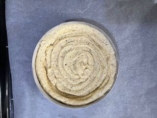 Un ricciolo di pasta è adagiato su un pezzo di carta oleata.