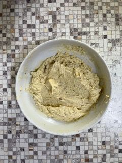 Una ciotola di pastella è appoggiata su un tavolo piastrellato.