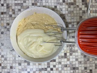 Una ciotola di pastella accanto a un mixer su un tavolo piastrellato.