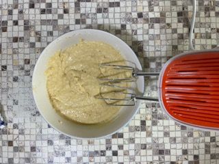 Una ciotola di pastella accanto a un mixer su un tavolo piastrellato.