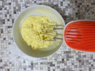 Una ciotola di pastella accanto a un mixer su un tavolo piastrellato.