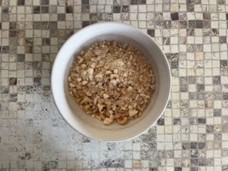 Una ciotola di noci tritate è appoggiata su un bancone piastrellato.