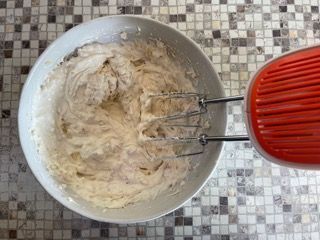 Una ciotola di panna montata viene mescolata con uno sbattitore elettrico.