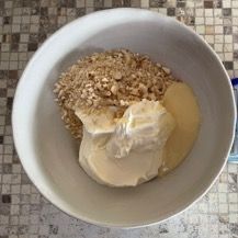 Una ciotola bianca piena di fiocchi d'avena e yogurt su un tavolo.