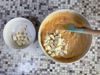 Una ciotola di cibo con un cucchiaio e una ciotola di formaggio su un tavolo.