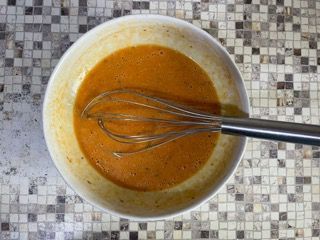 Una ciotola di salsa con una frusta dentro su un tavolo.