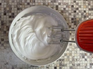 Una ciotola di panna montata accanto a un mixer rosso