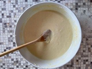 Una ciotola di pastella con un cucchiaio di legno dentro.