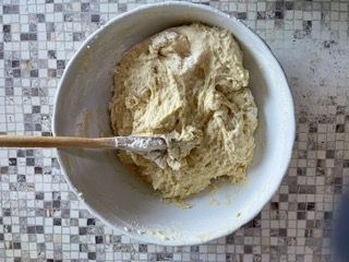 Una ciotola di impasto con un cucchiaio di legno dentro.