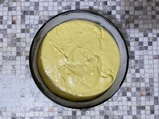 Una ciotola piena di liquido giallo è appoggiata su un bancone piastrellato.