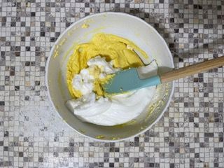 Una ciotola di pastella con panna montata e una spatola al suo interno.