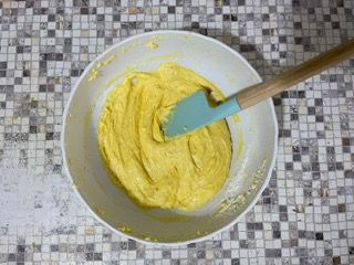 Una ciotola di pastella gialla con una spatola dentro.