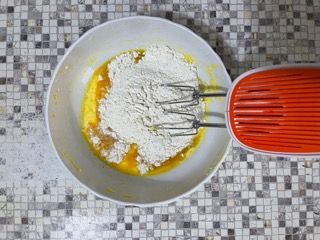 Una ciotola piena di farina e uova accanto a una planetaria.